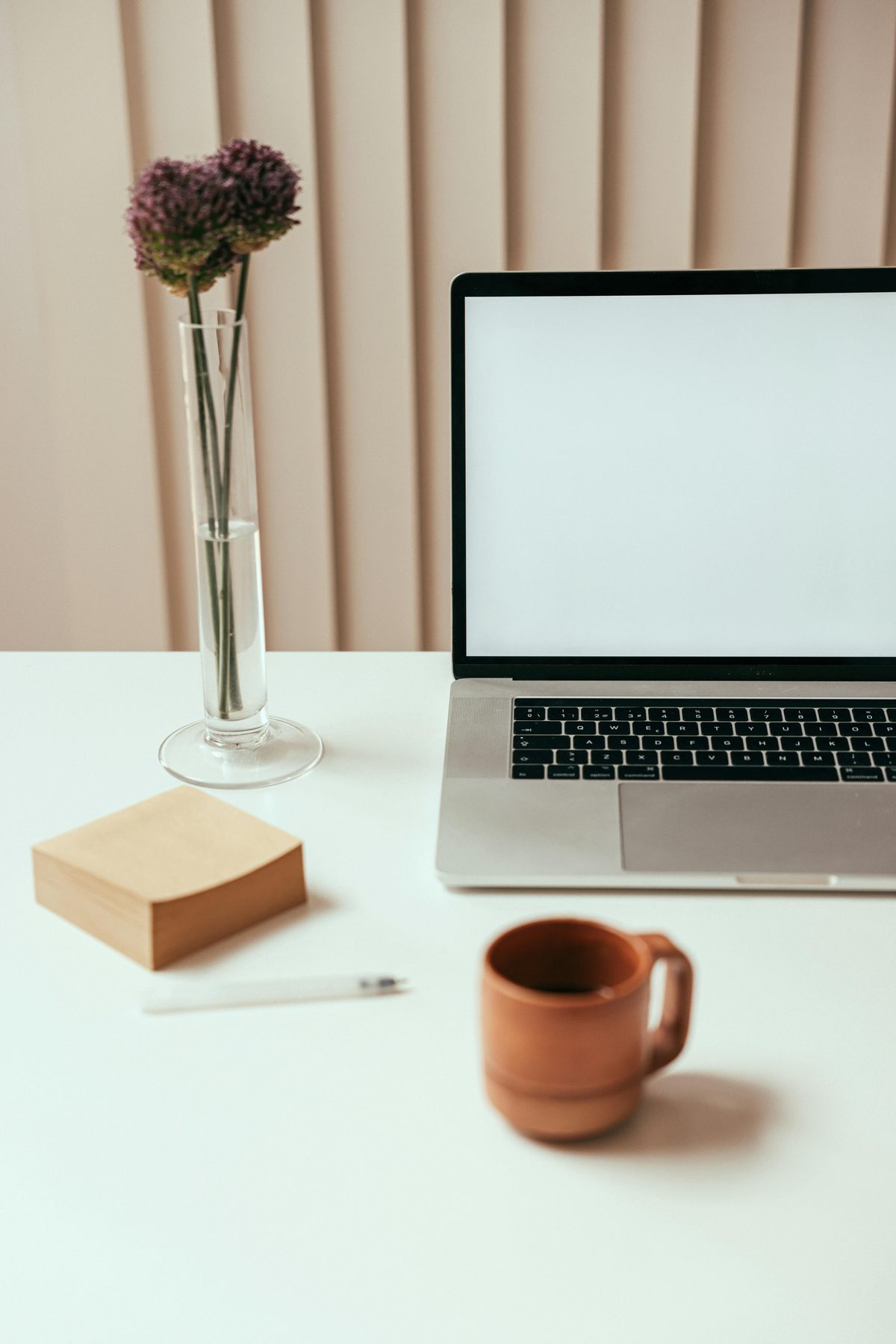 Minimal creative desk with a laptop, notebook, and coffee